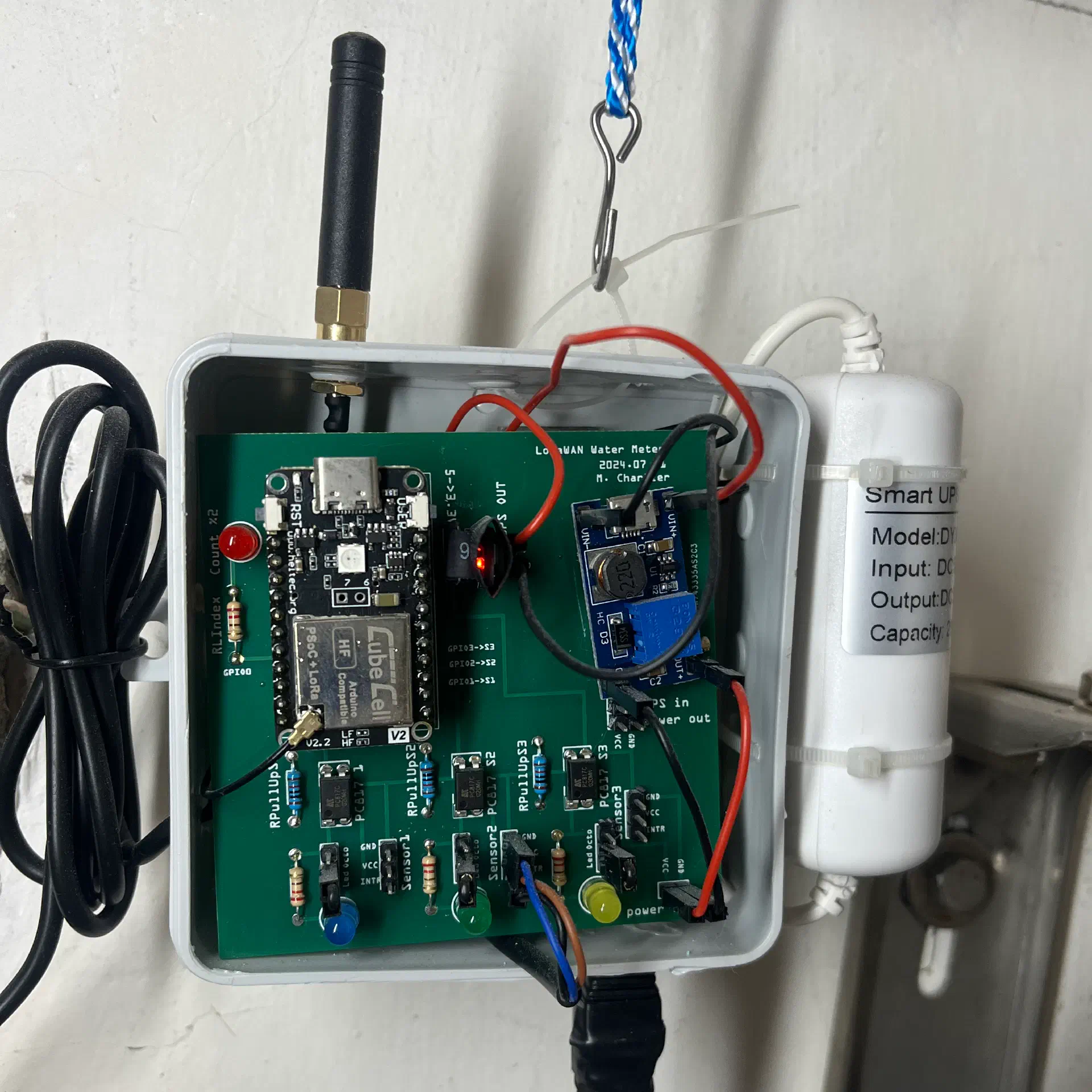 PCB inside the enclosure, showing the CubeCell, step-up converter, optocoupler, and UPS