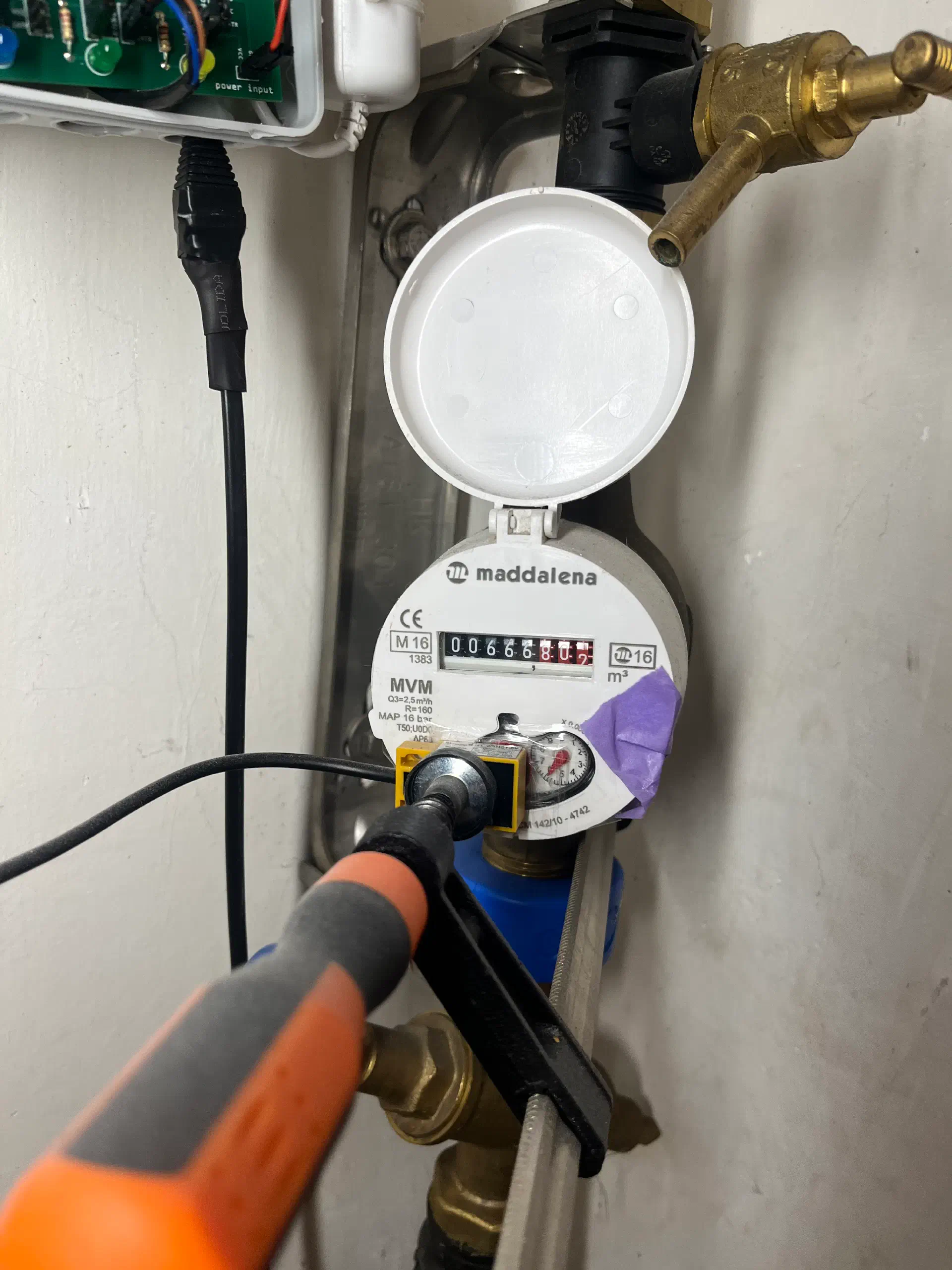 Close-up of the water meter with the inductive sensor positioned on the rotating dial
